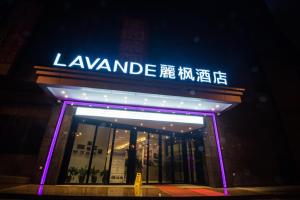 a man standing in the doorway of a store at night at Lavande Hotel (Liupanshui Ancient Town Branch) in Shuicheng