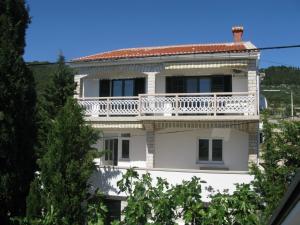 ein weißes Haus mit Balkon darüber in der Unterkunft Apartments Orhideja in Rab