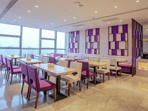 a restaurant with tables and purple chairs and windows at Lavande Hotel Handan Congtai Park New Century Plaza in Handan