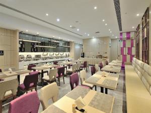 un restaurante con mesas y sillas y una cocina en Lavande Hotel (Siping Wanda Plaza Branch), en Siping
