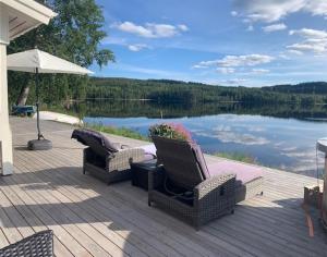 two chairs and an umbrella on a deck next to a lake at Galasjön 132 in Mellansel