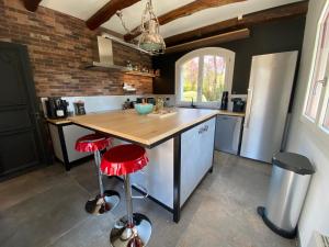 eine Küche mit einer Theke mit einem Kühlschrank und roten Stühlen in der Unterkunft Le Clos de Mon Père in Le Pont-de-Beauvoisin
