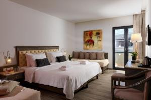 a bedroom with two beds and a couch at Castello City Hotel in Heraklio Town