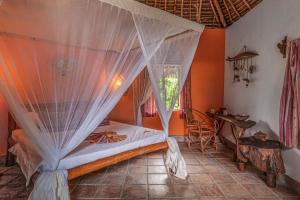 a bedroom with a bed with a mosquito net at Karamba Eco Boutique Hotel in Kizimkazi