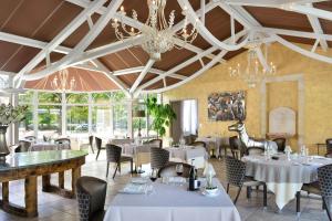 un restaurante con mesas y sillas blancas y lámparas de araña en Logis Domaine De Valaudran en Salbris