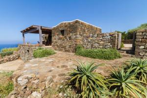 una casa de piedra en una colina con el océano en el fondo en Dammuso Kaddiuggia Antica Pantelleria, en Pantelleria