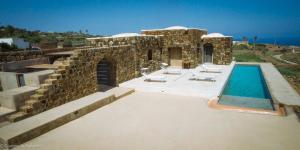 a stone house with a swimming pool and some chairs at Dammuso Kaddiuggia Antica Pantelleria in Pantelleria +9 photos