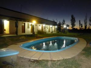 a swimming pool in front of a house at night at Complejo Los Parrales in General Alvear