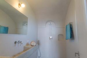 y baño con lavabo y ducha con toallas azules. en Dammuso Kaddiuggia Antica Pantelleria en Pantelleria