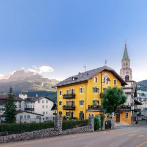 un edificio amarillo al lado de una calle en Ambra Cortina Luxury&Fashion Hotel, en Cortina dʼAmpezzo