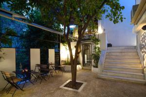 un patio con mesa, sillas y un árbol en Athens Green Apartments, en Atenas