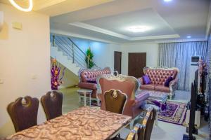 a room with chairs and a table and a staircase at Cc & Cg Homes Luxury 4 Bedroom Semi-Detached House In Abuja, Nigeria in Abuja