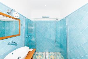 une salle de bain carrelée bleue avec un lavabo et une douche dans l'établissement La Borragine Rooms, à Positano 34 autres photos