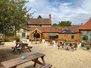 un grupo de mesas de picnic frente a una cabaña en The Greyhound Inn en Taunton