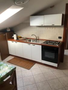 a kitchen with white cabinets and a sink and a stove at B&B Le Due Gemme Marsaglia in Marsaglia