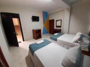 a hotel room with two beds and a television at Hotel El Andino in Cúcuta