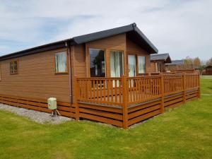 a large wooden cabin with a large deck at Sandy Glade Holiday Park in Burnham on Sea
