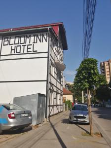 un edificio con un cartel para un hotel y un coche en Bloom Inn, en Niš