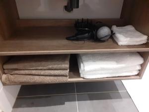 uma prateleira de madeira com toalhas e toalhas na casa de banho em Studio Le Ménascle em Saint-Georges-de-Luzençon