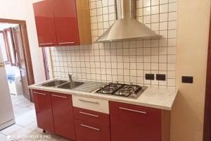 a kitchen with red cabinets and a stove and a sink at Villino Iris in Quartu SantʼElena