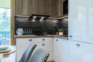 a kitchen with white cabinets and a table with chairs at Rezydencja Sobiczkowa Apartamenty in Zakopane
