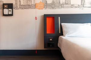 a bedroom with a bed with an orange and black headboard at easyHotel Birmingham in Birmingham