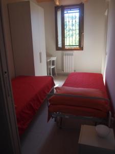 two beds in a room with red sheets and a window at Agriturismo Ardizio 43 in Pesaro