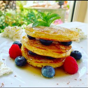 uma pilha de panquecas com bagas num prato em La Vittoria Boutique Hotel em Garda