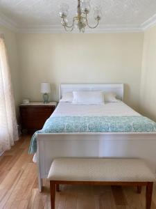 a bedroom with a bed with a chandelier and a bench at Breakwater Lodge in Lower Woods Harbour