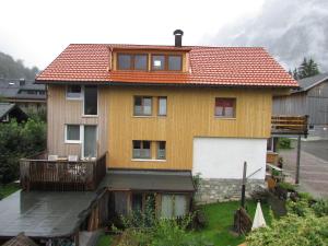 a yellow house with a balcony and a white garage at Haus Mittagspitze in Mellau