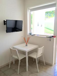 uma mesa branca e cadeiras com uma televisão na parede em Casa Mari em Marina di Ragusa