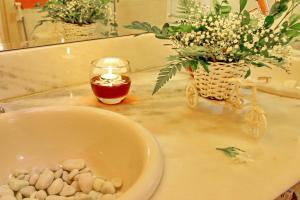 a bathroom sink with a candle and flowers on it at Villa Araçà - Boutique Hotel in Lauro de Freitas