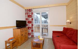 a living room with a red couch and a television at travelski home select - Résidence Les Bergers in Saint-Sorlin-dʼArves
