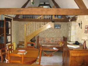 a living room with a wooden table and a staircase at Gîte de la pouvellerie in Fossemagne