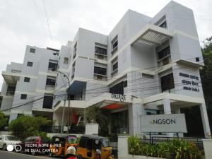 a white building with cars parked in front of it at Angson Apartment in Chennai