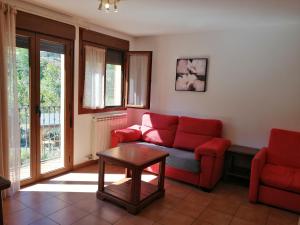 a living room with a red couch and a table at Apartamentos Mobison in Salinas de Bielsa