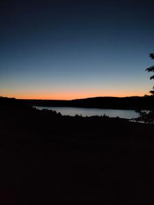 einen Sonnenuntergang über einem See mit einem Baum im Vordergrund in der Unterkunft Poggio San Giacomo in Baschi