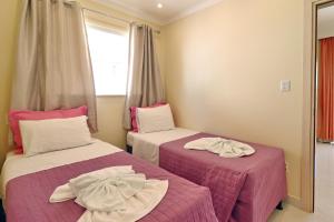 two beds in a room with pink and white sheets at Villa Araçà - Boutique Hotel in Lauro de Freitas