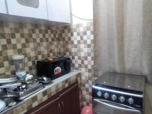 a small kitchen with a stove and a sink at Appartement ABS in Abidjan