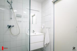 een witte badkamer met een douche en een wastafel bij Apartamenty na Podhalu in Nowy Targ