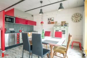 ノヴィ・タルクにあるApartamenty na Podhaluのキッチン(赤いキャビネット、テーブル、椅子付)