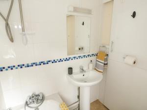 a white bathroom with a sink and a mirror at Cobbler's Cottage in Norwich +25 photos