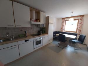 a kitchen with white cabinets and a table and chairs at Ferienhaus Fallenegger in Flachau