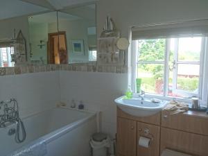 uma casa de banho com uma banheira, um lavatório e um espelho. em The Old Post Office B&B em Lymm
