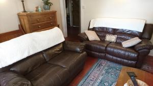 a living room with a leather couch and a chair at The Old Post Office B&B in Lymm