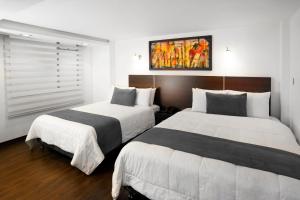 two beds in a hotel room with white and black at Hotel Torre del Bosque Pasto in Pasto