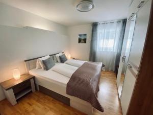 a bedroom with a large white bed and a wooden floor at Luxuriöses und modernes Apartment zum Wohlfühlen in Zirl