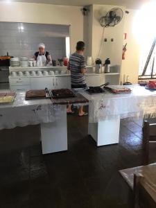two people standing in a kitchen preparing food at Carol Palace Hotel in Foz do Iguaçu
