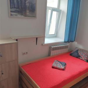 a small bedroom with a red bed with a window at Globe Hostel in Barnaul