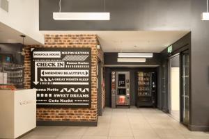 a lobby with a brick wall with signs on it at easyHotel Milton Keynes in Milton Keynes +30 photos